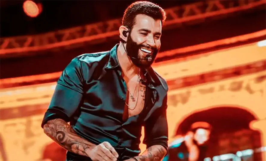 Gusttavo Lima se apresentando em show sertanejo com iluminação de palco.